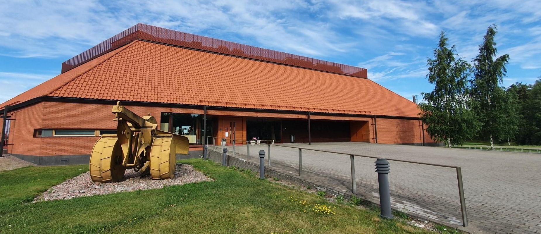 Museorakennus ja edessä keltainen maansiirtokone
